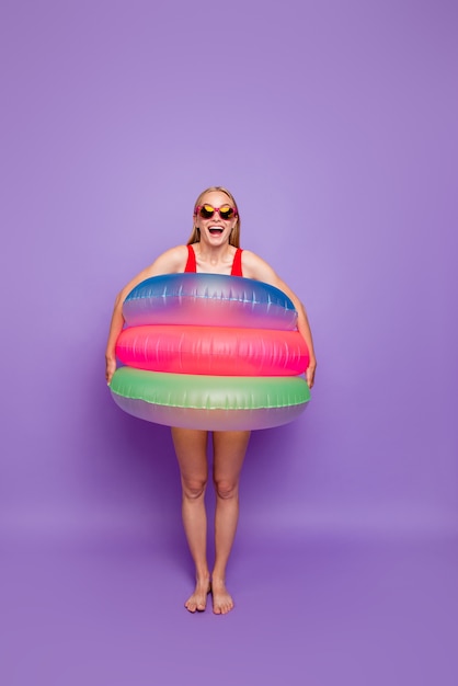 Portrait of girl with colorful float around waist isolated on violet flotador