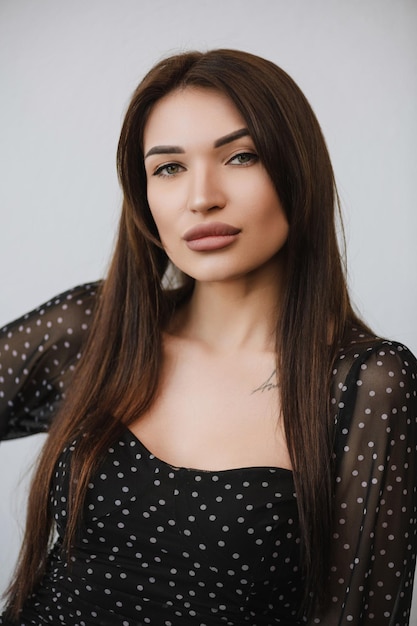 Portrait of a girl with dark hair in dark clothes on a white background