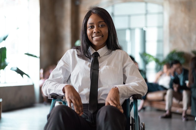 Portrait of a girl with a disability in a wheelchair smiling in her office lobby