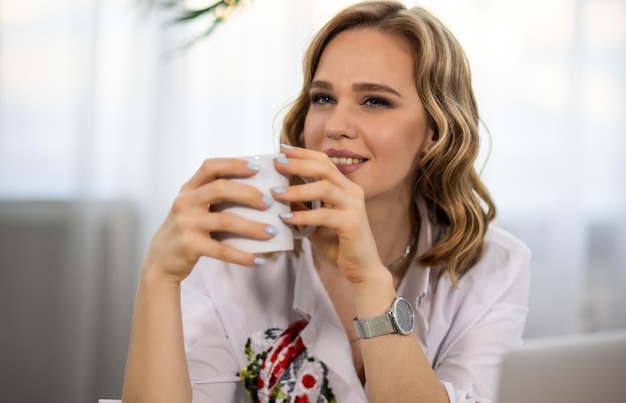 Portrait of a girl with a hairstyle makeup and manicure with a cup of drink