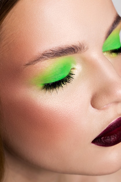 Portrait of a girl with a light green make-up and burgundy lips with matte lipstick.