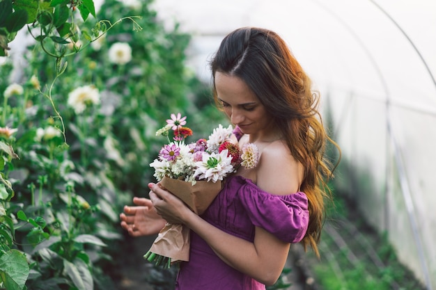 Portrait girl with long hair in the greenhouse. Walk in the flower garden. Girl and flowers. Floristics.