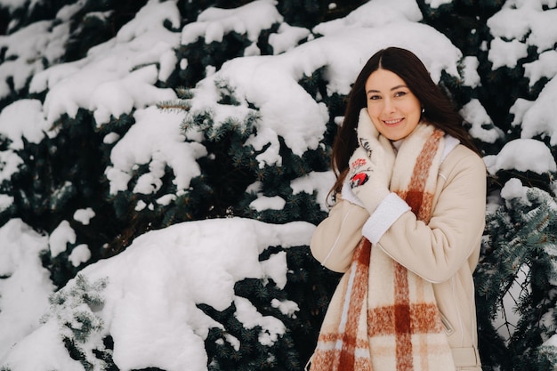 Portrait of a girl with long hair in mittens in a winter forest Snowy winter