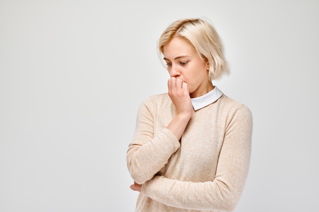 Portrait of girl with sad face worried biting nails on white background Nerves stress uncertainty concept