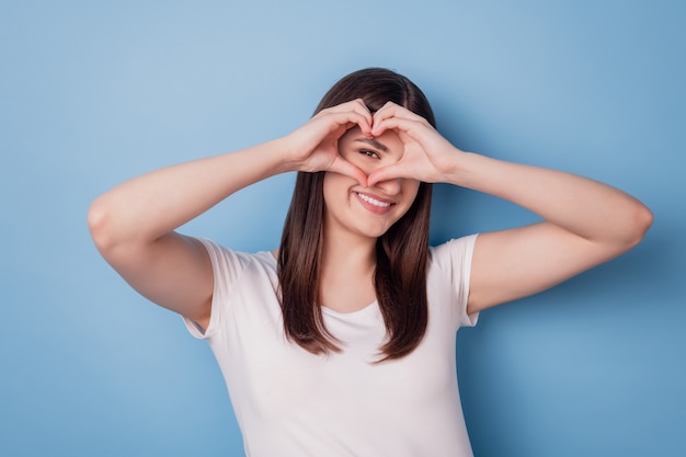 Portrait of girlfriend lady show heart sign beaming smile cover eye on blue background