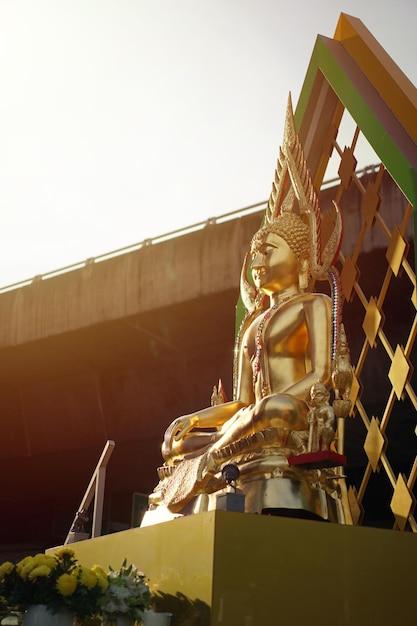 Portrait Gold Buddha statue with expressway behind and sunlight effect