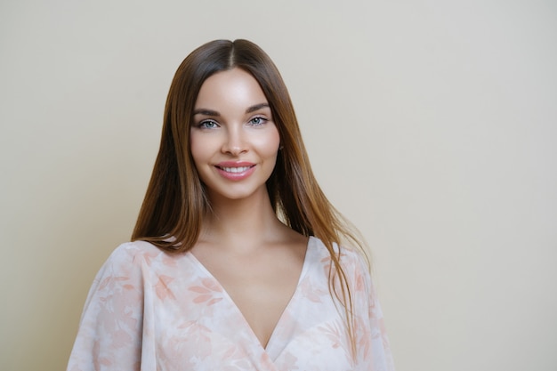 Portrait of good looking dark haired European woman wears stylish clothes, applies makeup, isolated over brown background, has natural look, fresh clean skin.