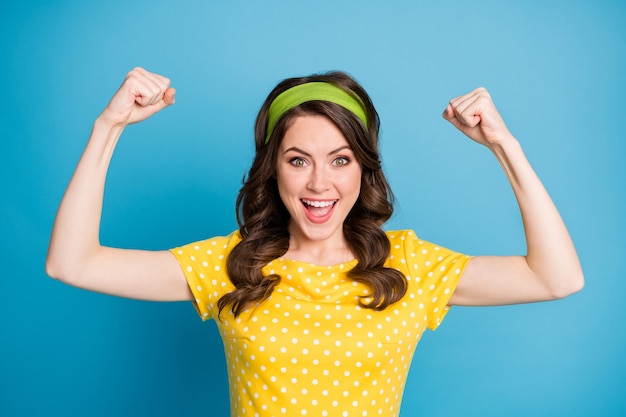 Photo portrait of good mood energetic girl show her biceps hands isolated over blue color background