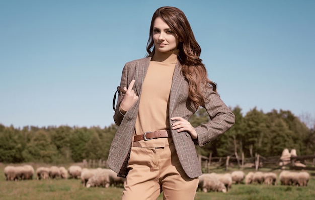 Portrait of a gorgeous brunette woman in an elegant checkered brown jacket posing on country landscape