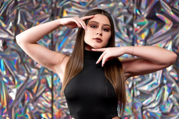 Portrait of a gorgeous elegant girl in a black sexy dress Posing against a shiny background