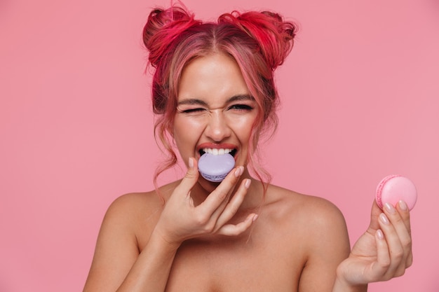 Portrait of gorgeous shirtless young woman with colorful hairstyle eating macaron cookies