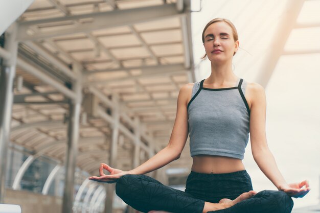 Portrait of gorgeous young woman practicing yoga outdoor in city.