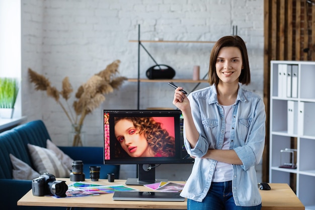 Portrait of graphic designer working in office with laptop,monitor,graphic drawing tablet and color palette.Retouching images in special program.Retoucher workplace in photo studio.Creative agency.