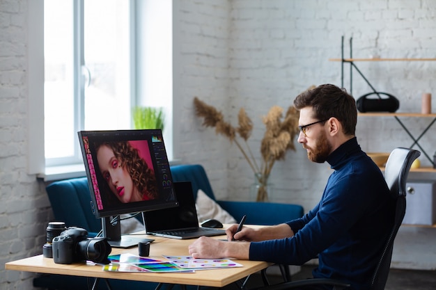 Portrait of graphic designer working in office with laptop,monitor,graphic drawing tablet and color palette.