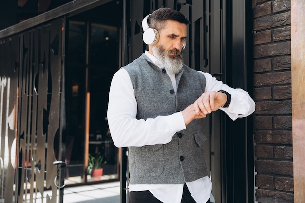 Portrait of a gray bearded and brutal man spending time on the clean streets of the city.