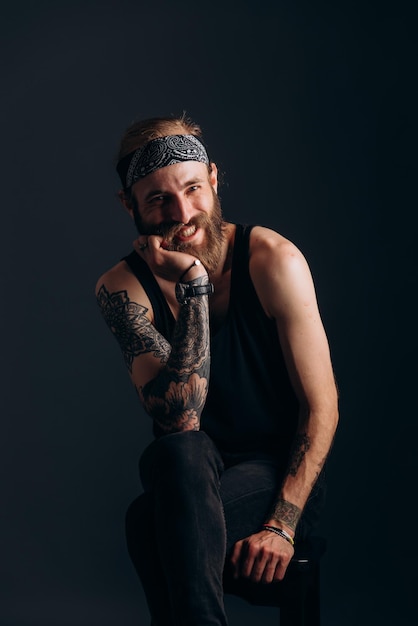 Portrait of a guy with a beard and tattoos on a dark background hipster