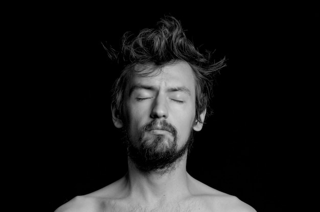 Portrait of a guy with a beard and tousled hair on a black background