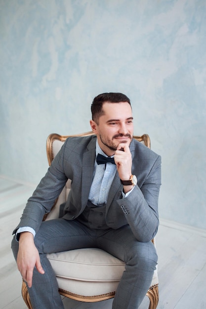 Portrait of a handsome adult man in a gray suit in the studio The groom is waiting for the bride Wedding