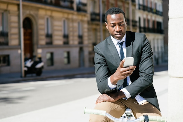 Portrait of Handsome african man smiling when he is using his mobile in the street.