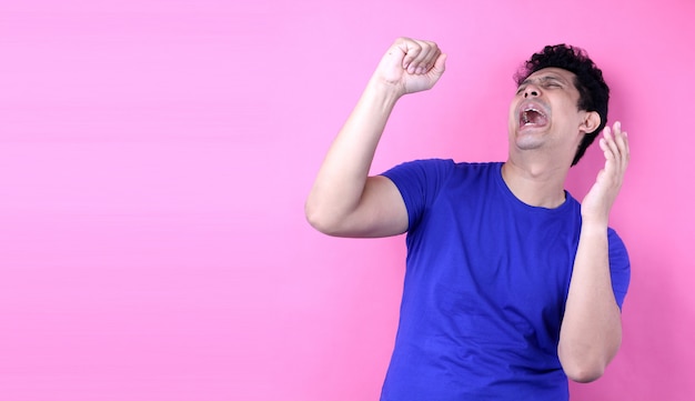 Portrait Handsome Asia man singing loud while standing  on pink background in studio