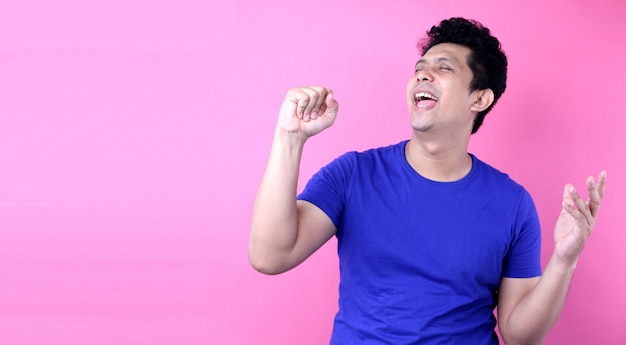 Portrait Handsome Asia man singing loud while standing  on pink background in studio