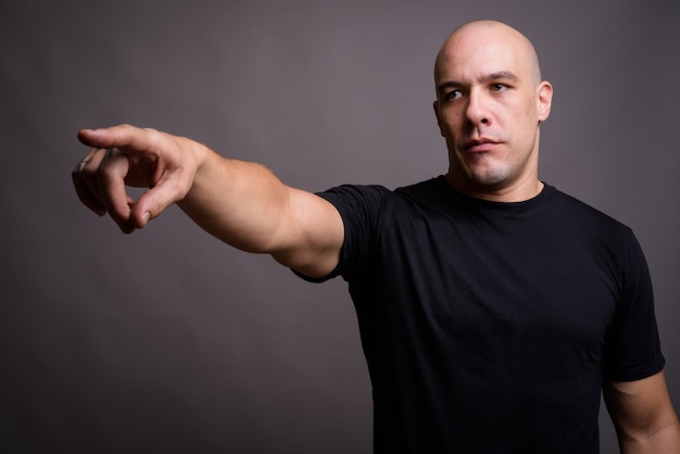 Portrait of handsome bald man against gray background