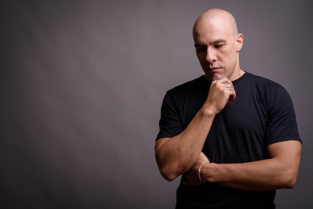 Portrait of handsome bald man against gray background