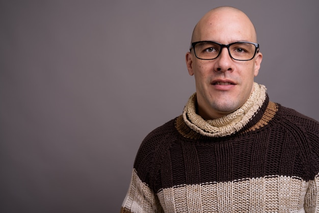 Portrait of handsome bald man against gray background