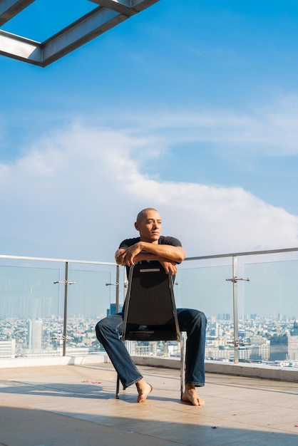 Portrait of handsome bald man sitting and thinking outdoors in city