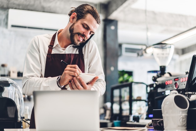 Portrait of handsome bearded barista man receiving order from customer