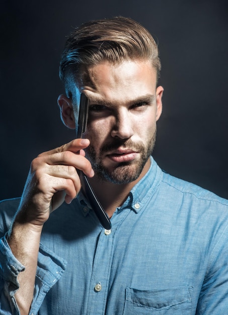 Portrait handsome bearded guy holding dangerous razor near face young man with beard and mustache