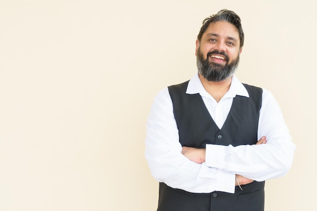 Portrait of handsome bearded Indian businessman against plain background