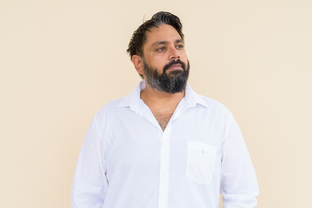 Portrait of handsome bearded Indian man against plain background