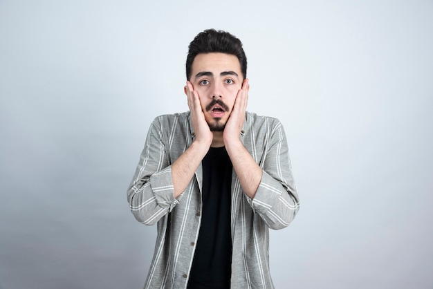 Portrait of handsome bearded man standing and looking on white wall.