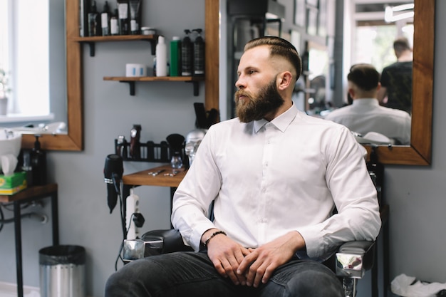 Portrait of handsome bearded man with fashionable hairstyle and beard at barber shop.