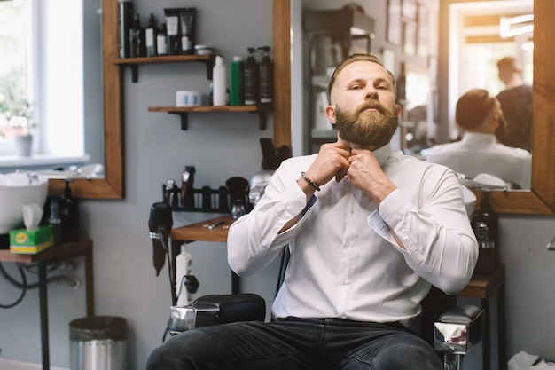 Portrait of handsome bearded man with fashionable hairstyle and beard at barber shop.