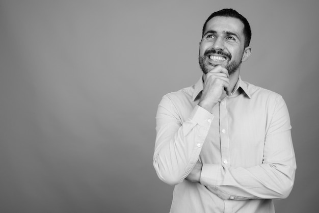 Portrait of handsome bearded Persian businessman on gray in black and white