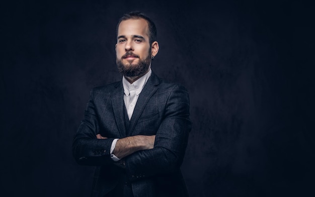 Portrait of handsome bearded stylish male, wearing an elegant suit on a dark background.