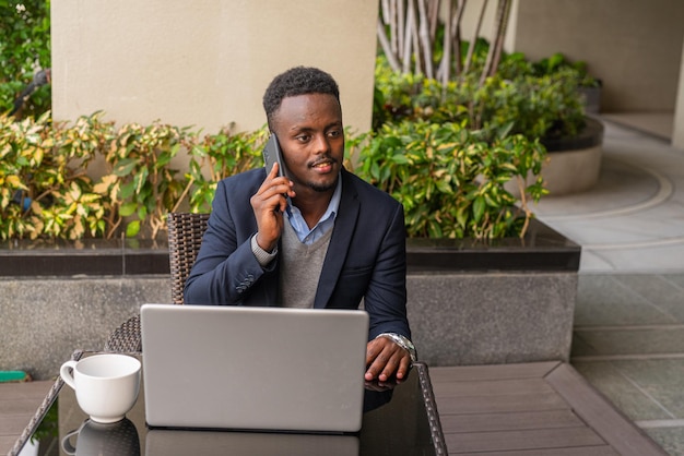 Portrait of handsome black African businessman using laptop computer