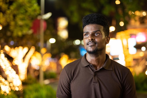 Portrait of handsome black man in city at night thinking