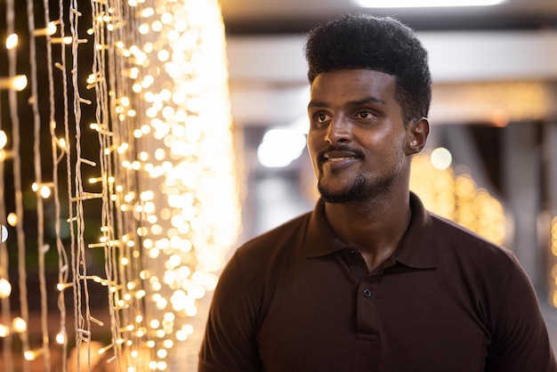 Portrait of handsome black man in city at night thinking