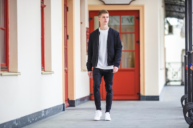 Portrait of handsome boy teenager walking down the street along the shops