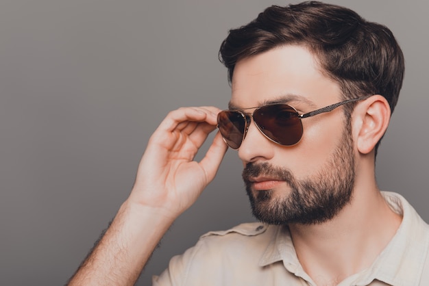 Portrait of handsome brutal bearded man touching his spectacles