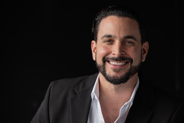 Portrait of handsome businessman against black background smiling