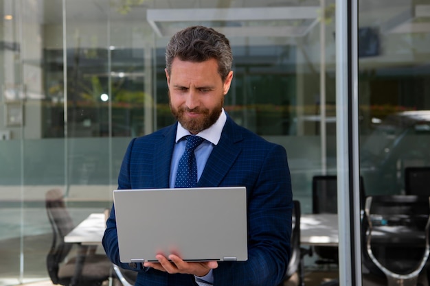 Portrait of handsome businessman using laptop outdoor