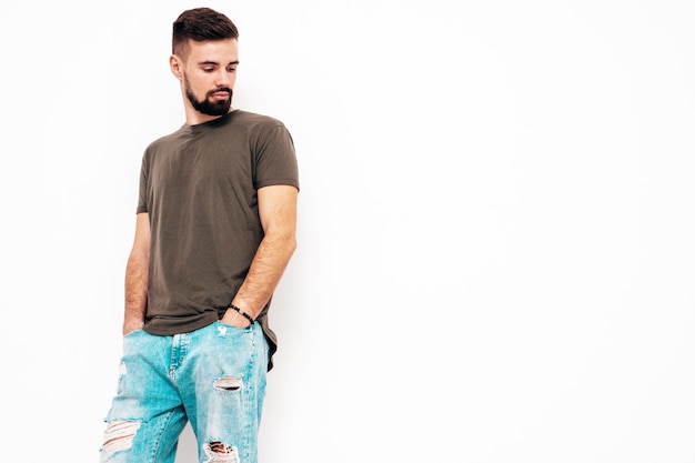 Portrait of handsome confident stylish hipster lambersexual modelMan dressed in Tshirt and jeans Fashion male isolated on white wall in studio