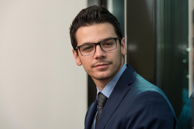 Portrait Of Handsome Confident Young Businessman Standing Arms Crossed