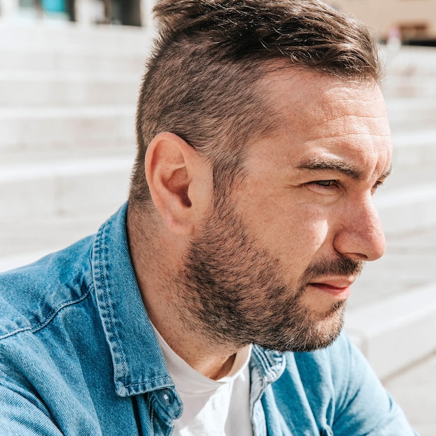 Portrait of a handsome hipster man in a jean jacket in a big city on the street a life style