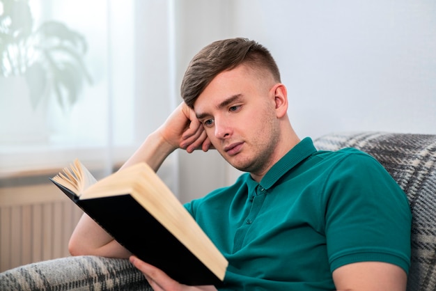 Portrait of handsome intelligent guy, young attractive serious man reading an interesting book