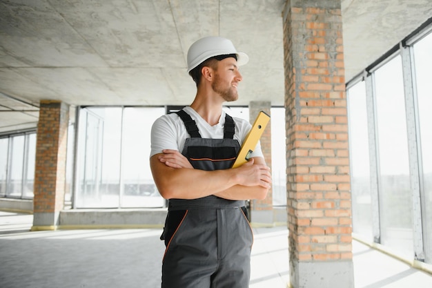 Portrait of handsome male builder in overalls and hard hat